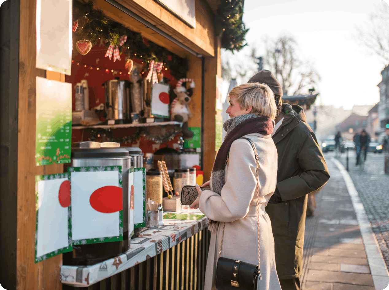 Smiling customer makes a contactless payment at an outdoor kiosk using a smartphone and Viva.com payment terminal.