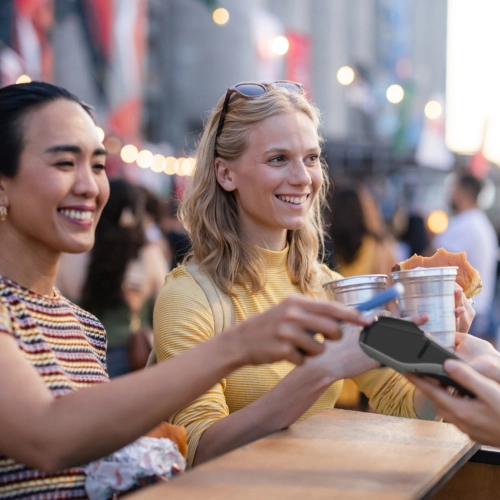 Customers using contactless payment at an outdoor event, illustrating Viva.com smart checkout flow for ticketing and entertainment businesses.