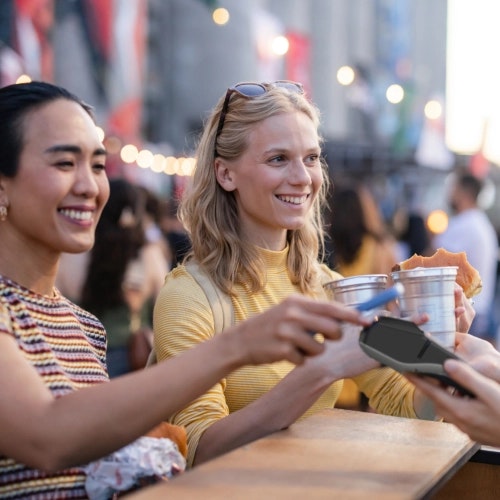Customers using contactless payment at an outdoor event, illustrating Viva.com smart checkout flow for ticketing and entertainment businesses.