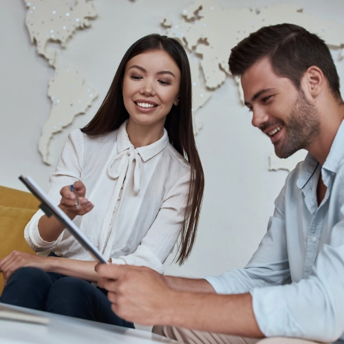 Two professionals smiling while reviewing information on a tablet, representing Time Travel’s collaboration with Viva.com to improve business efficiency and payment processes.