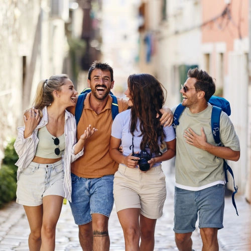 Group of young travelers walking through a sunny street, laughing and enjoying their trip symbolizing smooth travel experiences and effortless payments powered by Viva.com and Time Travel.