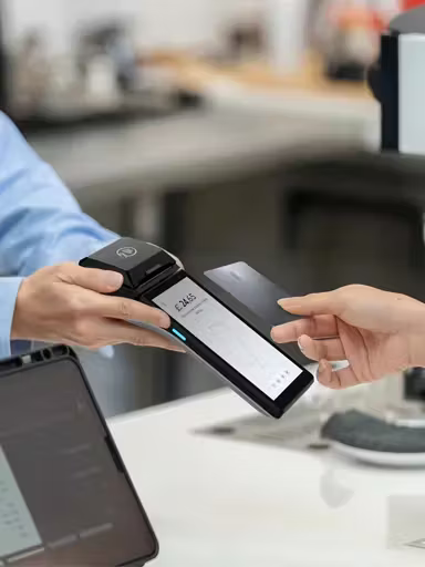 Customer making a contactless card payment on a Viva.com POS terminal held by merchant in a retail environment