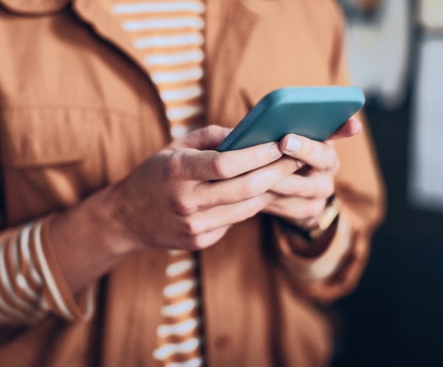 Κοντινό πλάνο σε άτομο που κρατά smartphone, συμβολίζοντας την υποχρεωτική υιοθέτηση της μεθόδου πληρωμής IRIS από τους Έλληνες εμπόρους μέσω της Viva.com.