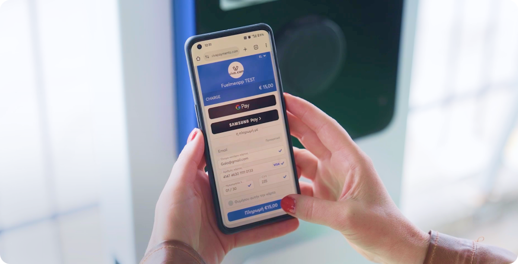 Närbild på händer som använder en smartphone för att slutföra betalningen för laddning av elfordon via Viva.com Smart Checkout-gränssnittet, med visning av digitala plånboksalternativ och betalningsformuläret för en MCChargers-laddstation