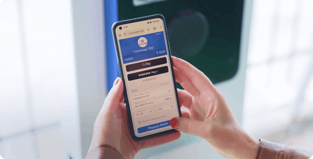Close-up of hands using smartphone to complete EV charging payment through Viva.com Smart Checkout interface, showing digital wallet options and payment form for MCChargers station