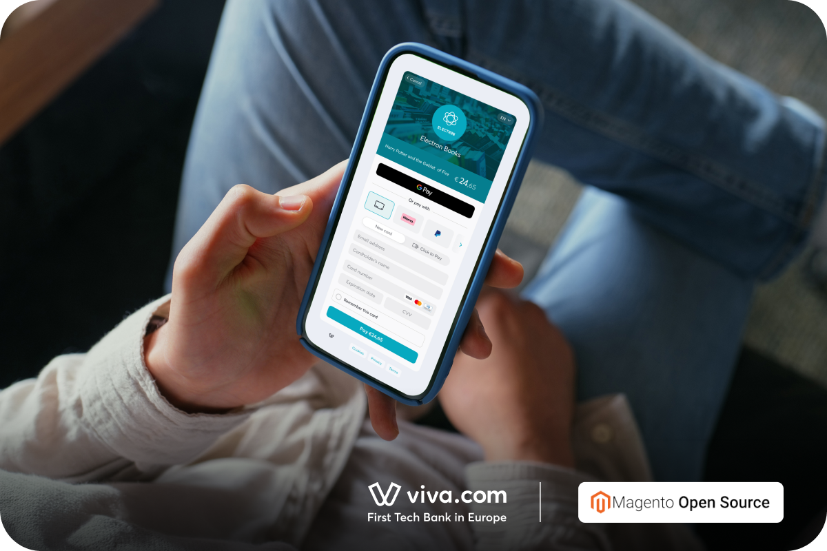 Person, der holder en smartphone med Viva.com checkout-siden, som viser flere betalingsmuligheder, bl.a. Google Pay, Klarna og kortbetaling, i en Magento Open Source-webshop, med logoerne for Viva.com og Magento Open Source nedenunder