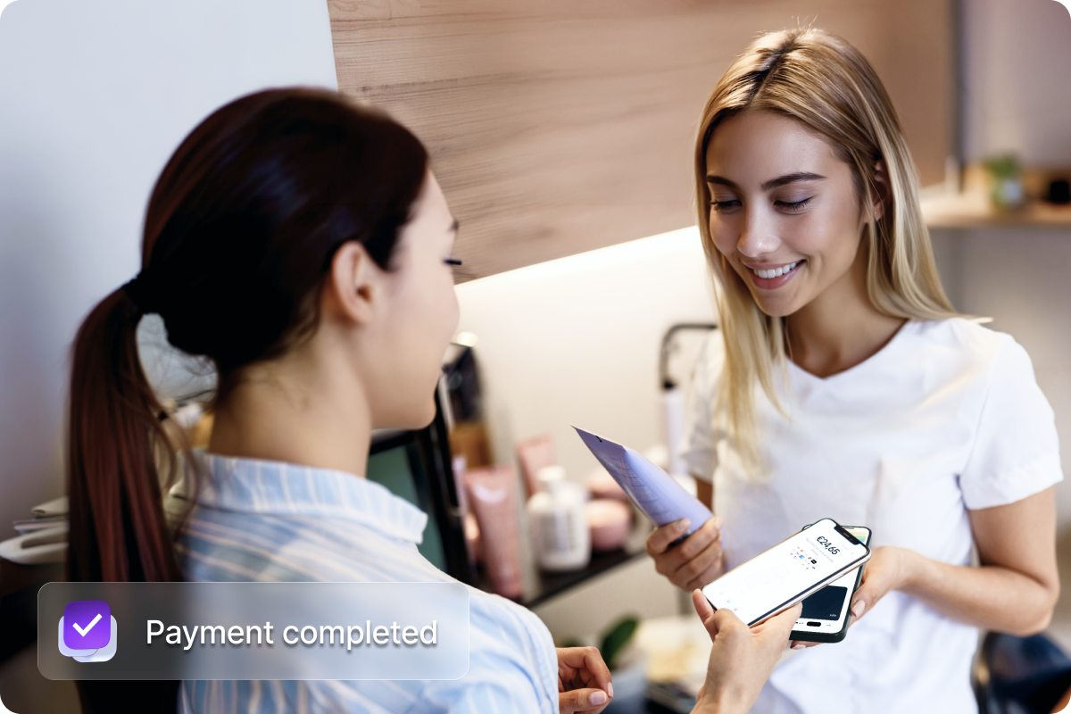 Klant die met een smartphone een contactloze betaling uitvoert in een schoonheidssalon met de mobiele betaaloplossing van Viva, met een bevestiging ‘Betaling voltooid’ op het scherm.