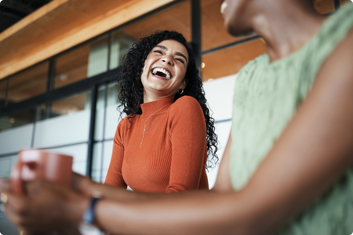A Viva.com employee laughing and engaging with colleagues in a bright, modern office setting, reflecting the company's positive workplace culture and collaborative team environment