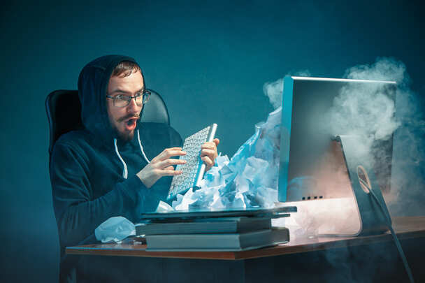 Homem estressado em frente a um computador com defeito devido à presença de vírus de computador.