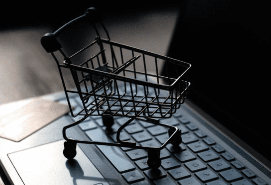 Carrinho de compras em cima de um computador simbolizando as lojas virtuais