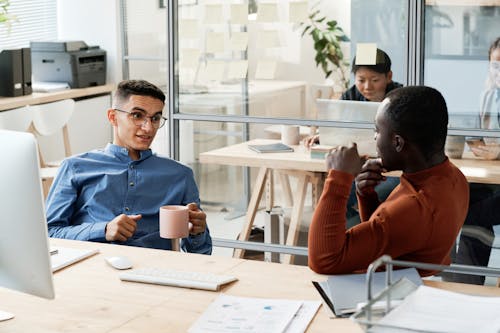 Uomo con tazza davanti a pc e collega