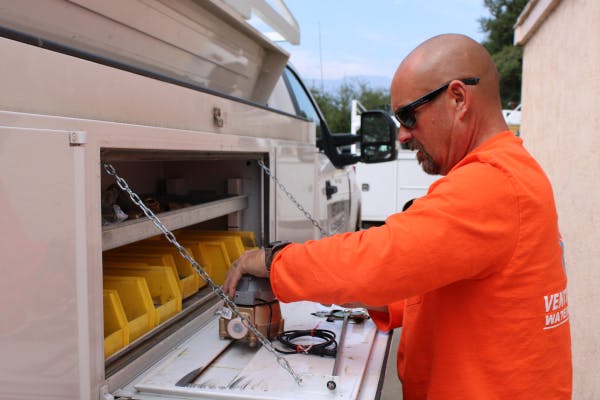 A worker with a piece of water equipment on a mobile truck workbench