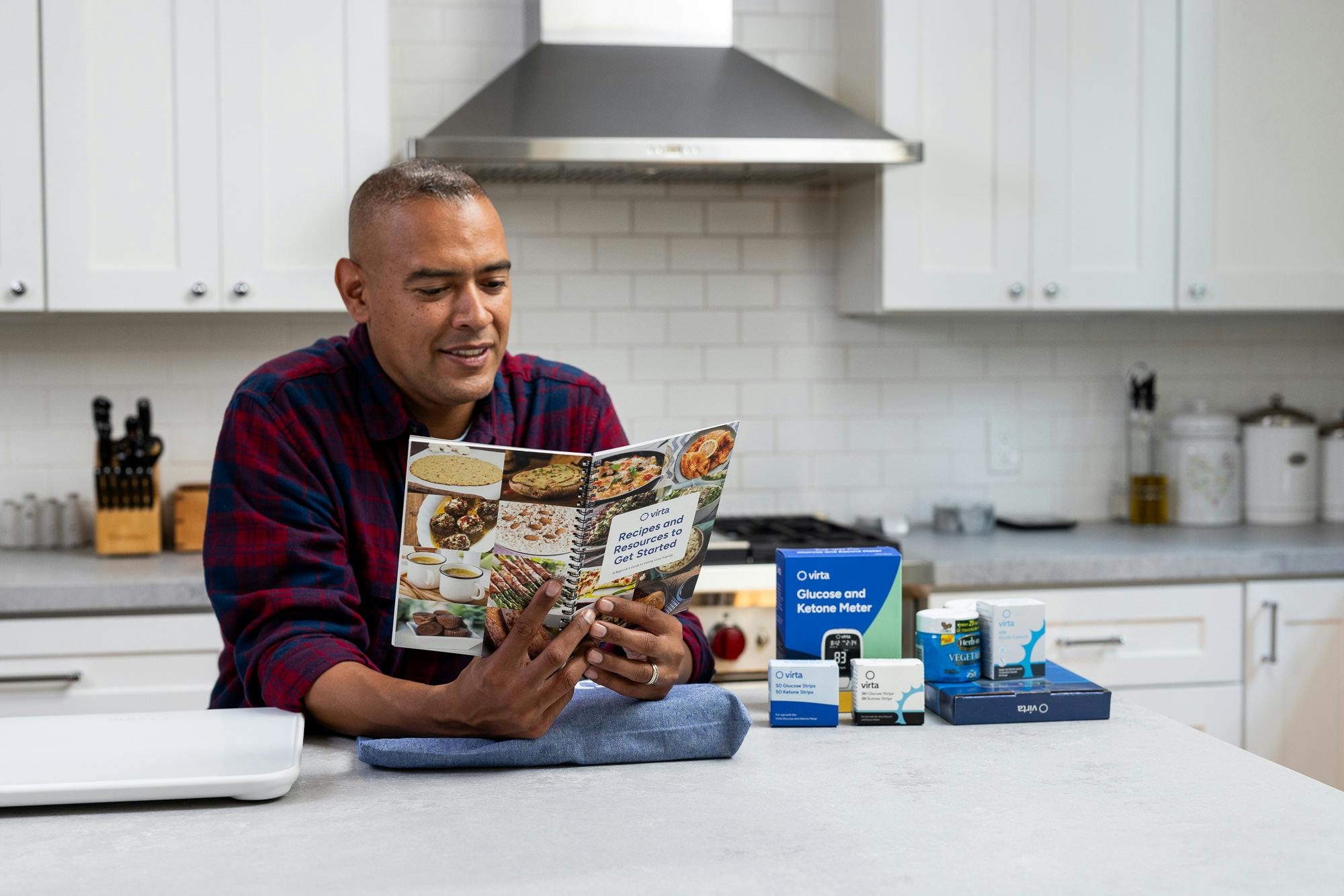 man reading recipe book in kitchen with Virta Starter Kit next to him on the counter