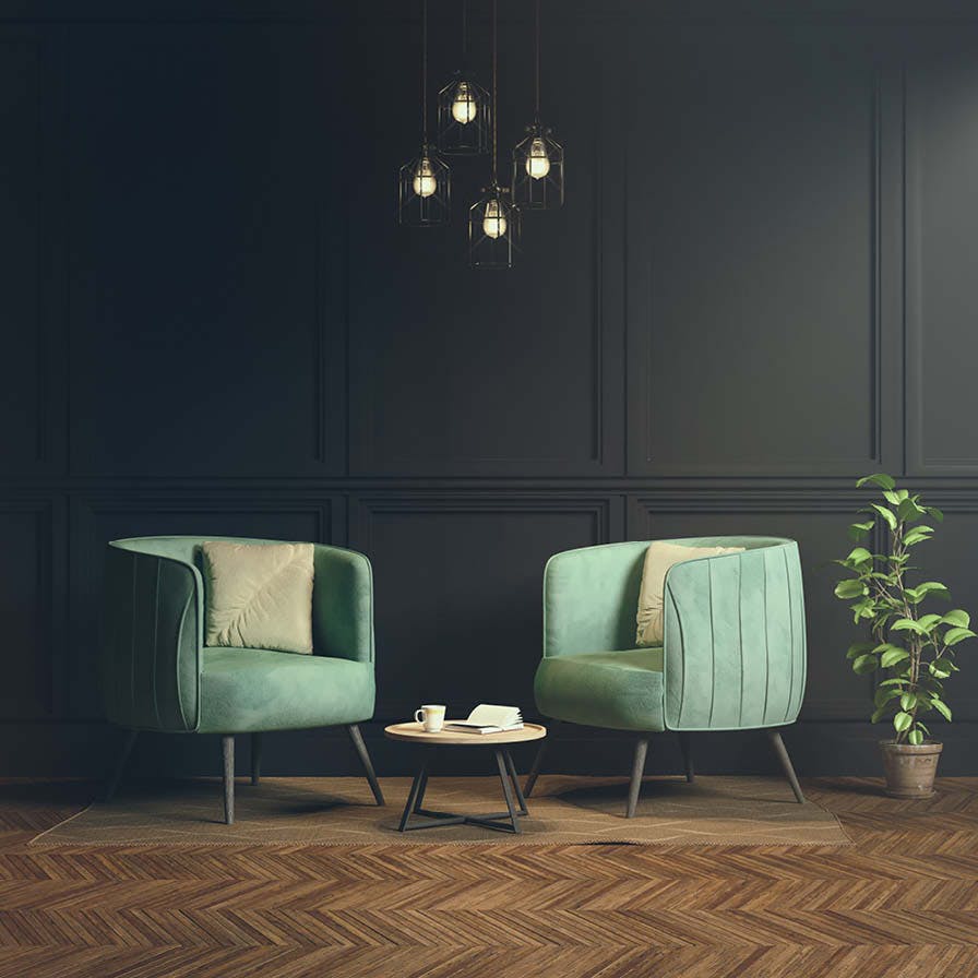 Two light teal chairs against a dark green wall and wooden floor