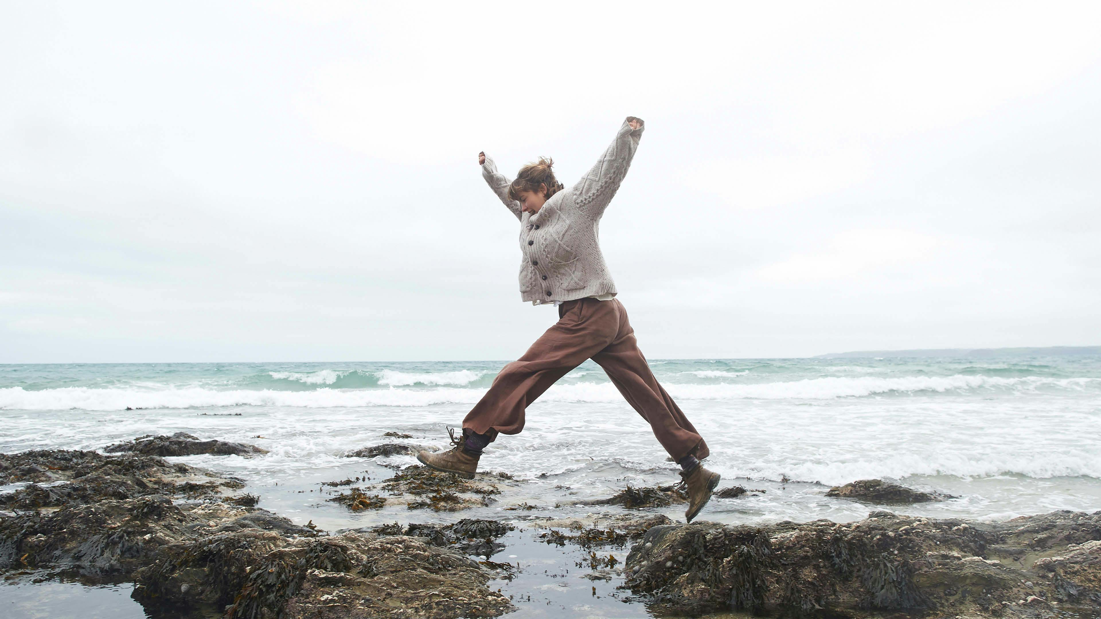 Woman walking on sea rocks