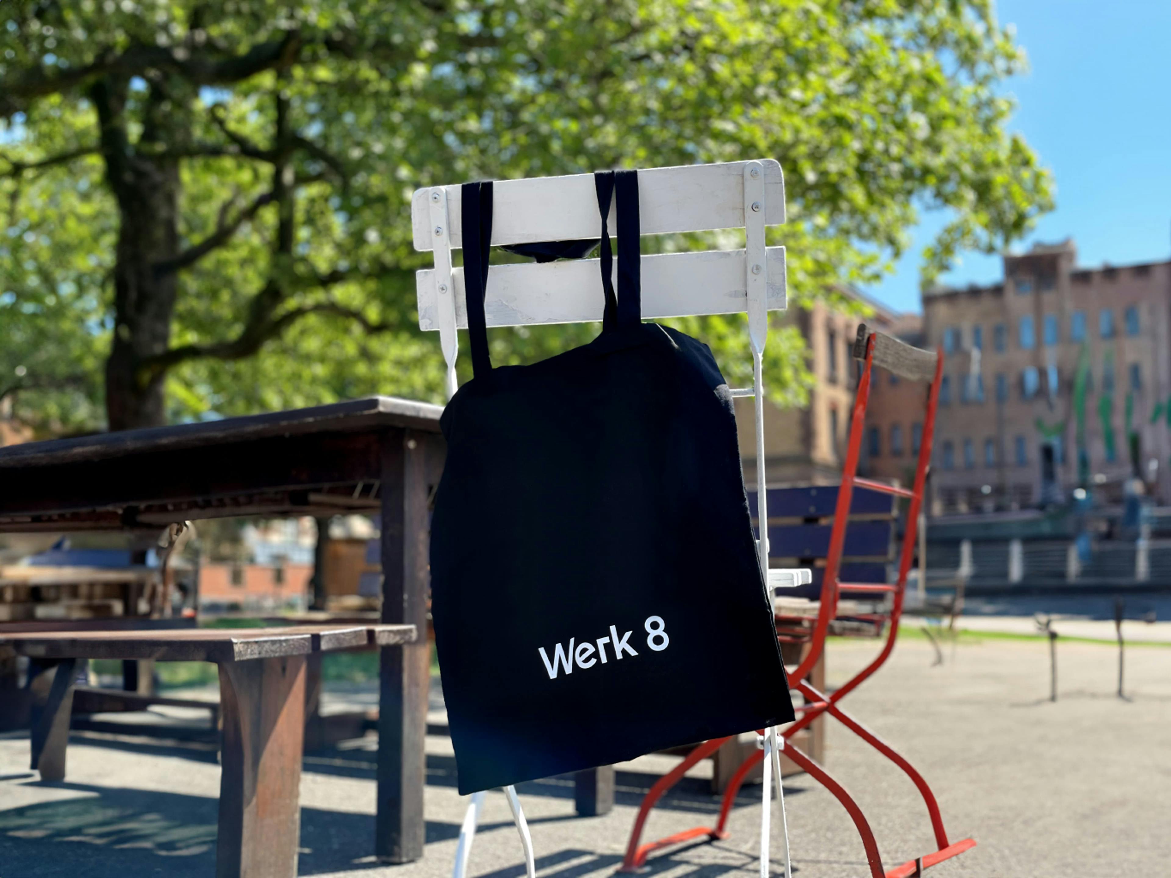 Stofftüte mit dem Werk 8 Logo an einem Stuhl hängend