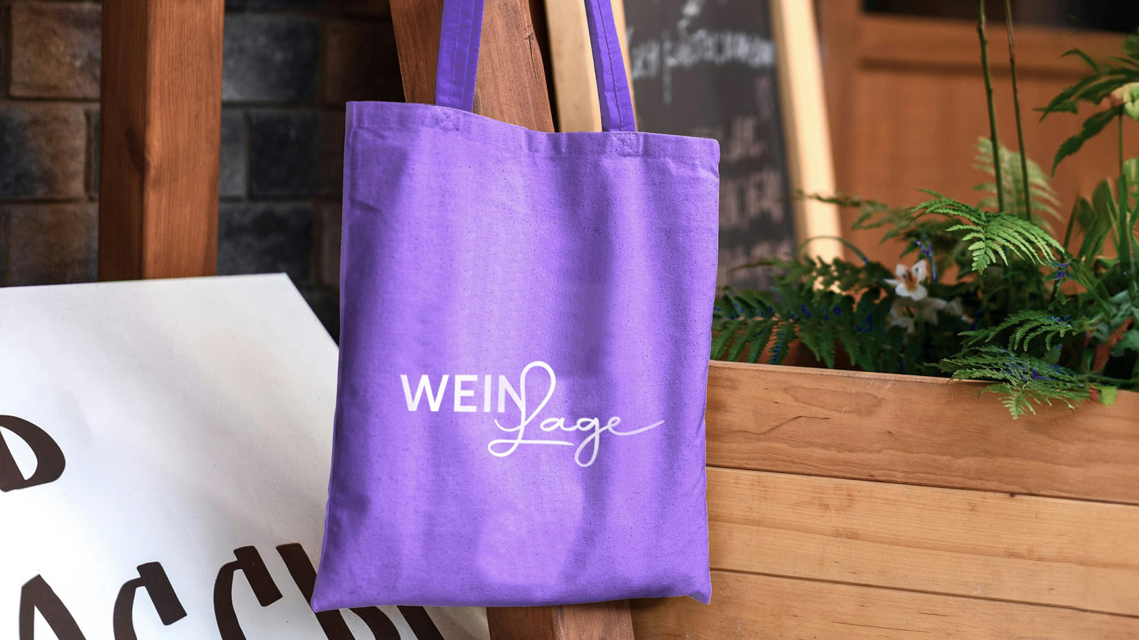 Bild zeigt lilane Trage-Tasche auf der das weiße Weinlage Logo prangert