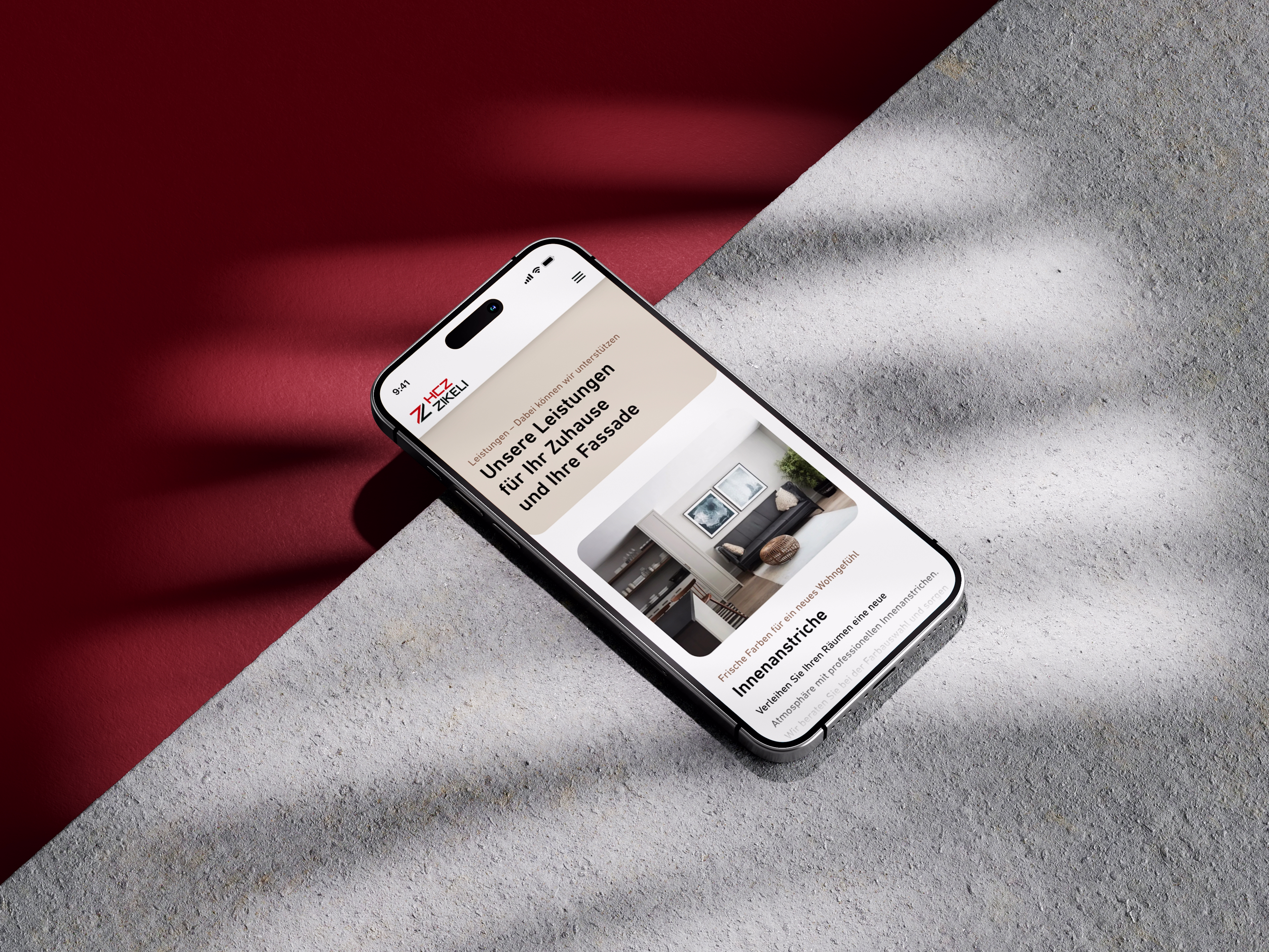 iPhone auf rotem und grauem Untergrund mit geöffneter Website-Ansicht der Website des Malerbetriebs Zikeli
