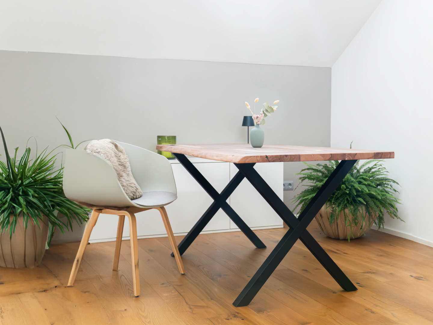 Moderner Massivholz-Esstisch mit schwarzem X-Gestell im hellen Esszimmer mit Pflanzen