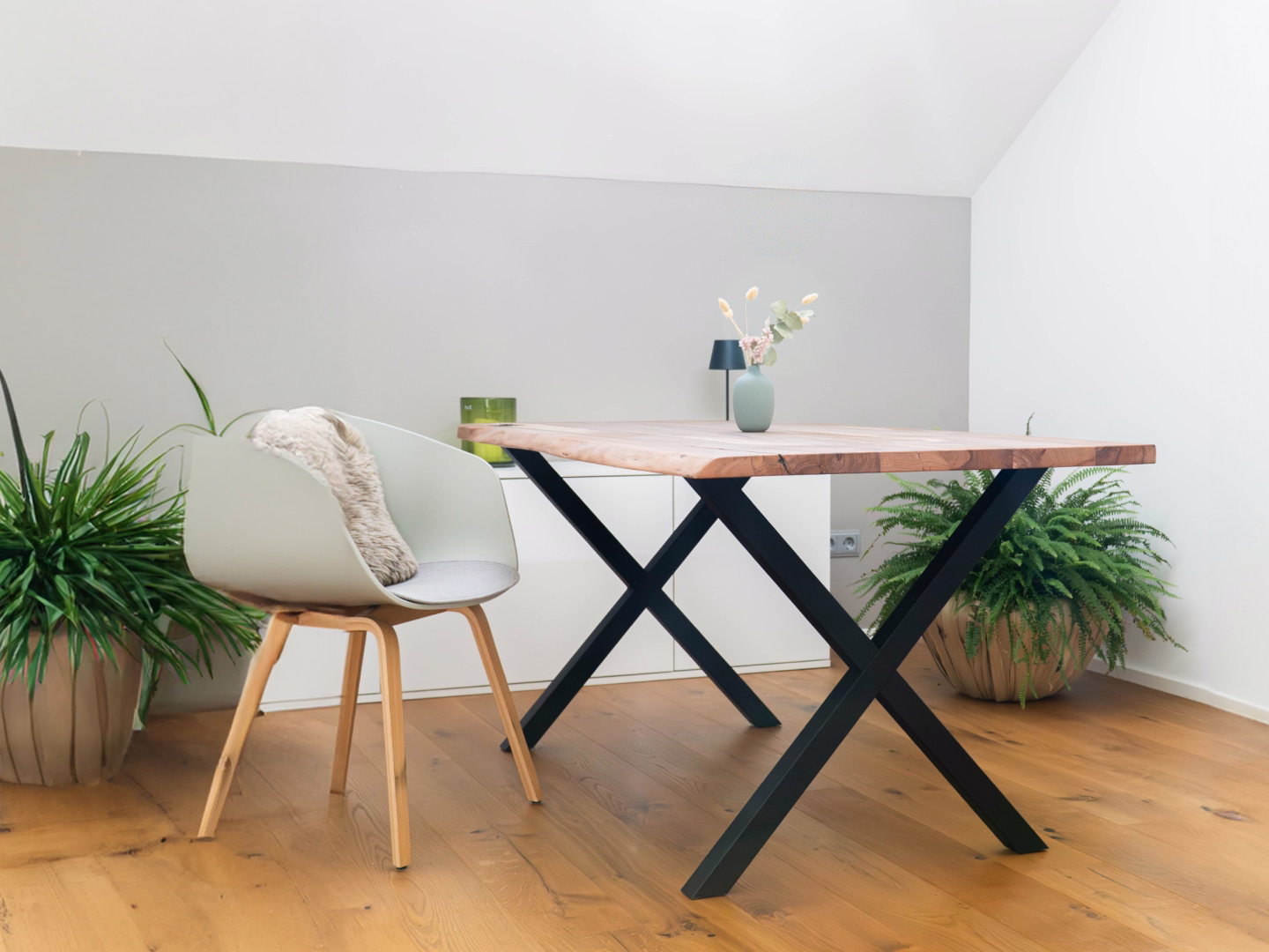 Moderner Massivholz-Esstisch mit schwarzem X-Gestell im hellen Esszimmer mit Pflanzen