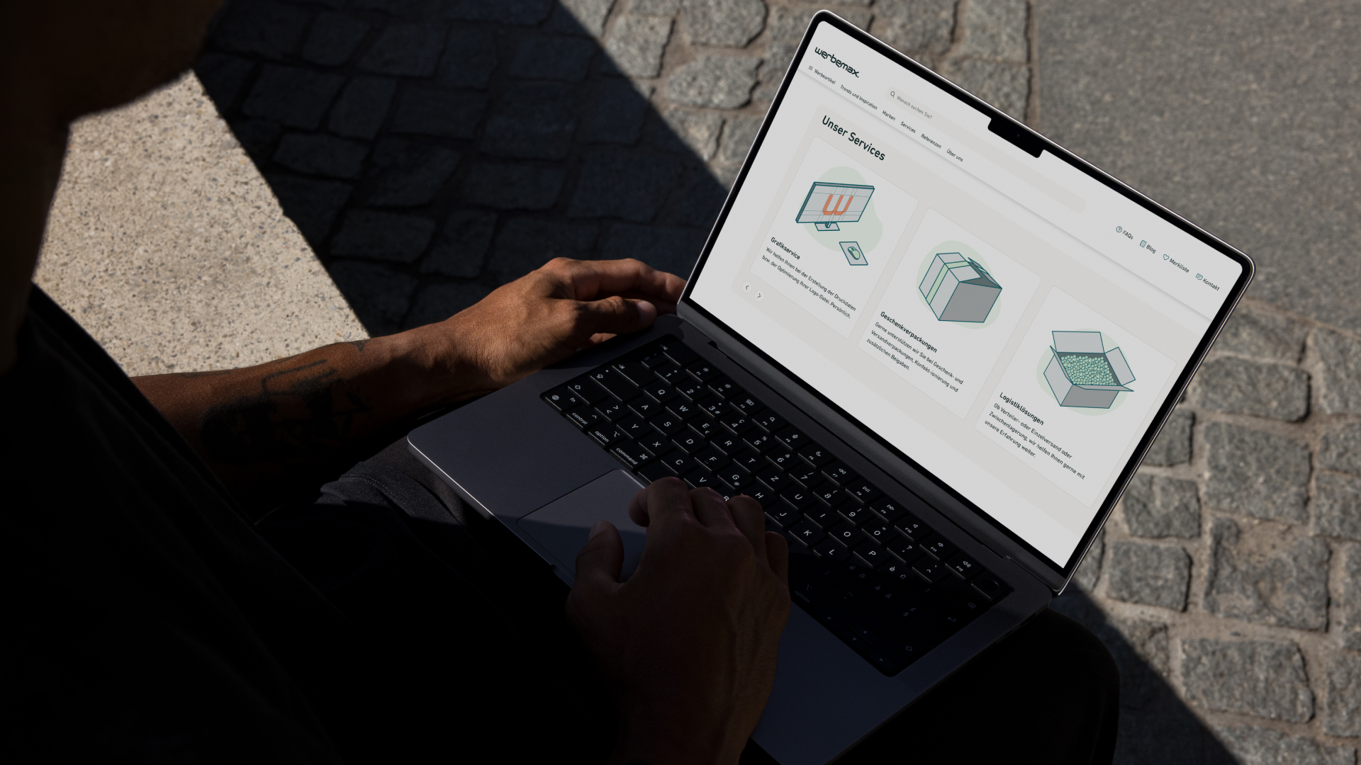Hände tippen auf MacBook Pro im Freien, Bildschirm zeigt Services-Seite mit drei Illustrationen