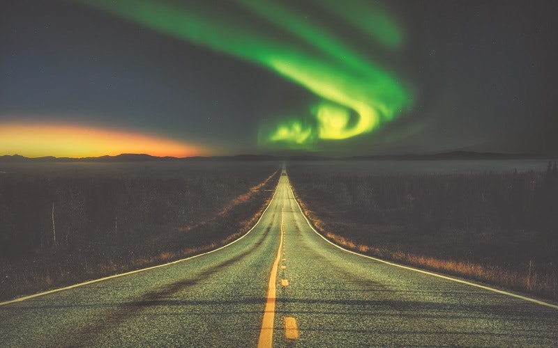 A road underneath the northern lights in Iceland