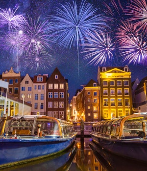 Fireworks going off above a classic scene of houseboats, canals and warehouses in Amsterdam