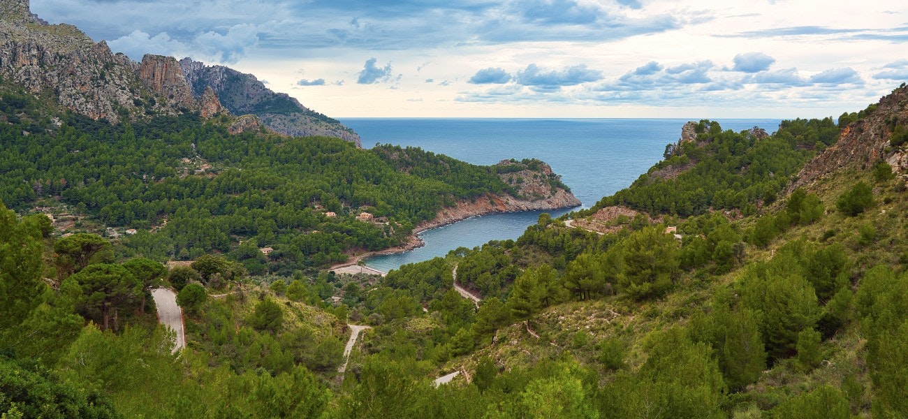 Great panoramic view of the surrounding mountains and a winding small road down to the coast. Hiking adventure. Traveling. Spanish island of Mallorca (Majorca).