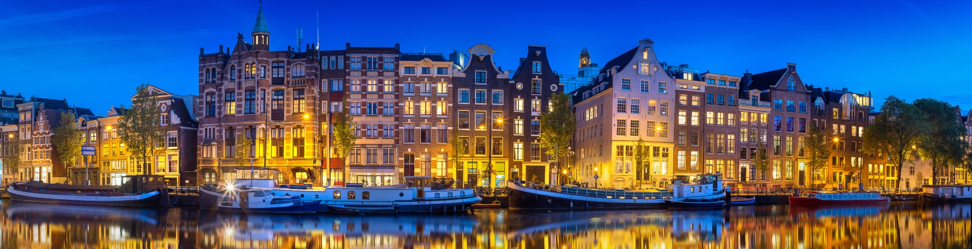 Cityscape of Amsterdam at night with reflection of buildings on water, Holland Netherlands