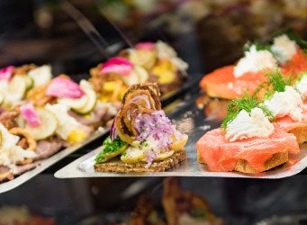 Danish smorrebrod traditional open sandwich at Copenhagen food market store. Selection of fish and beef sandwiches, smoked salmon, cold cuts banner panorama.