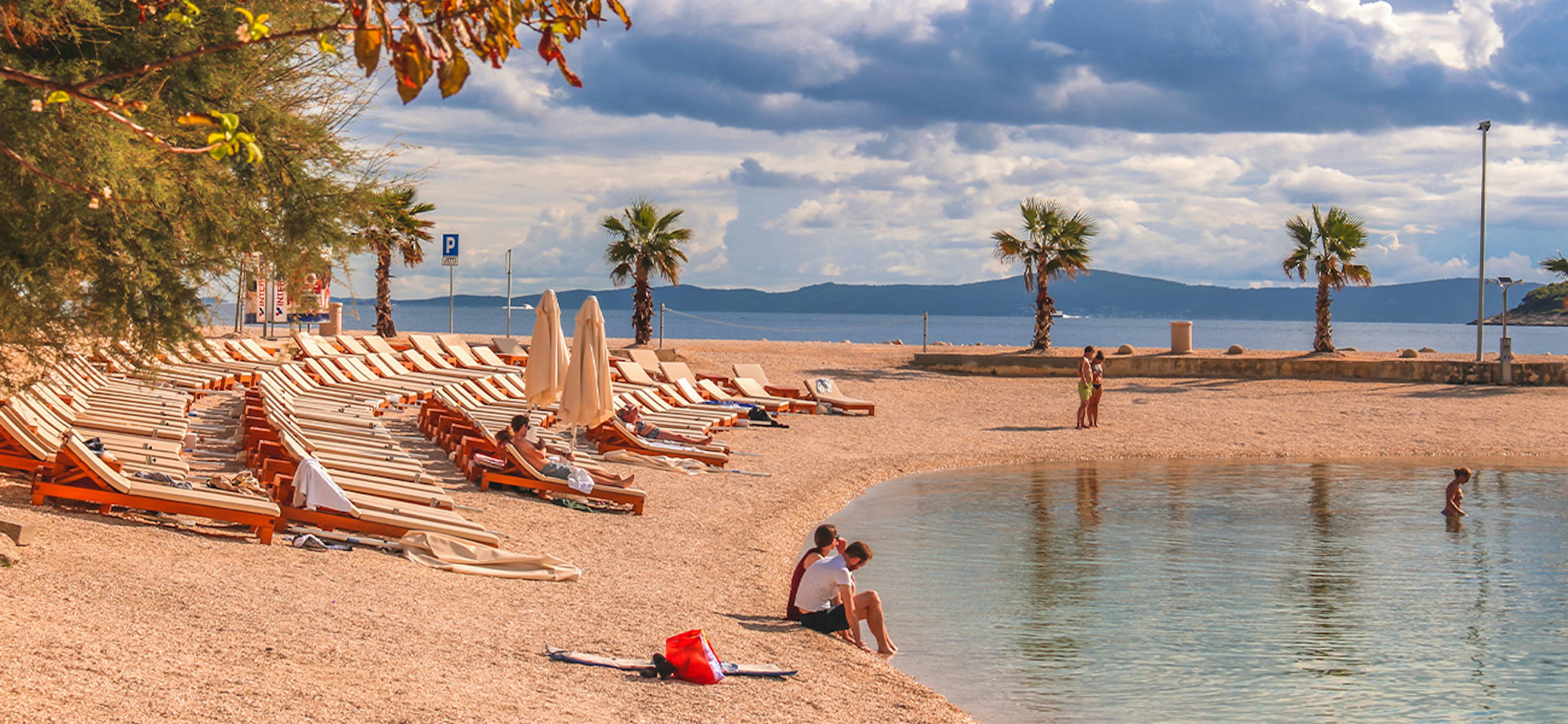 People bathing at the famous Croatian beach Kasuni (Croatian: Plaa Kasjuni), by the Adriatic Sea, in Split, Croatia.