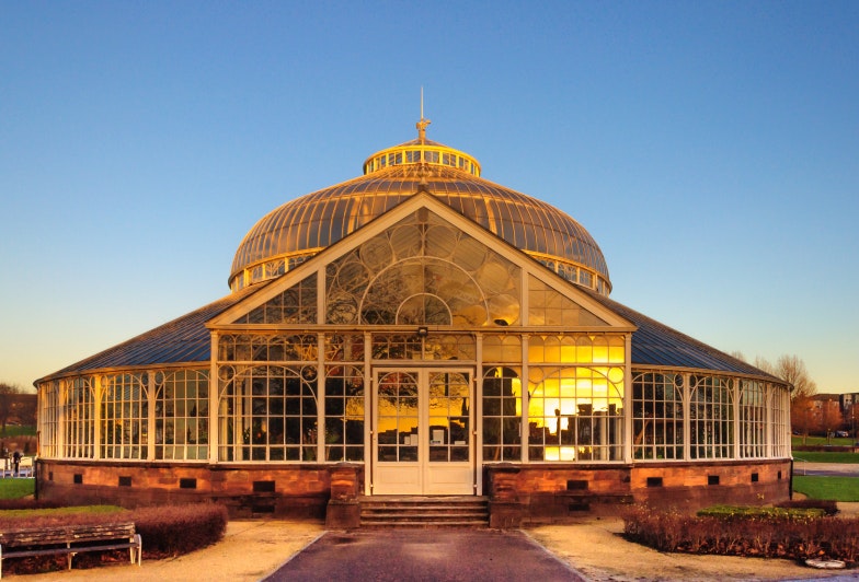 Rear elevation of the Winter Gardens of the People's Palace, Glasgow Green, Glasgow, Scotland with a reflection in the glass of the city skyline at sunset