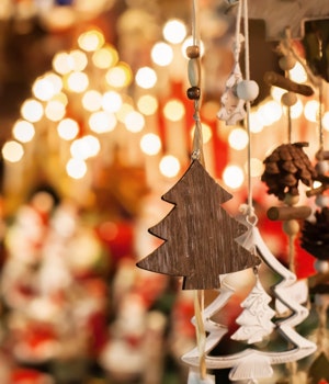 A decorative Christmas tree hanging in the foreground with Christmas lights in the background