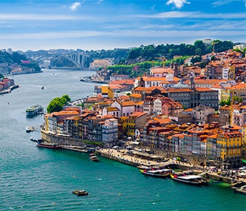 The charming cityscape of Porto with green lush areas in the background, a beautiful bridge and river in Portugal