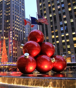 Red christmas decorations in New York City with flags and skyscrapers in the background
