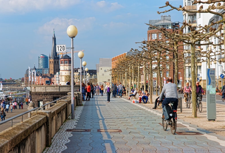 Rhine embankment promenade in the Old city center of Dusseldorf in Germany. Tourists nearby. It is the capital of Rhine Westphalia region.