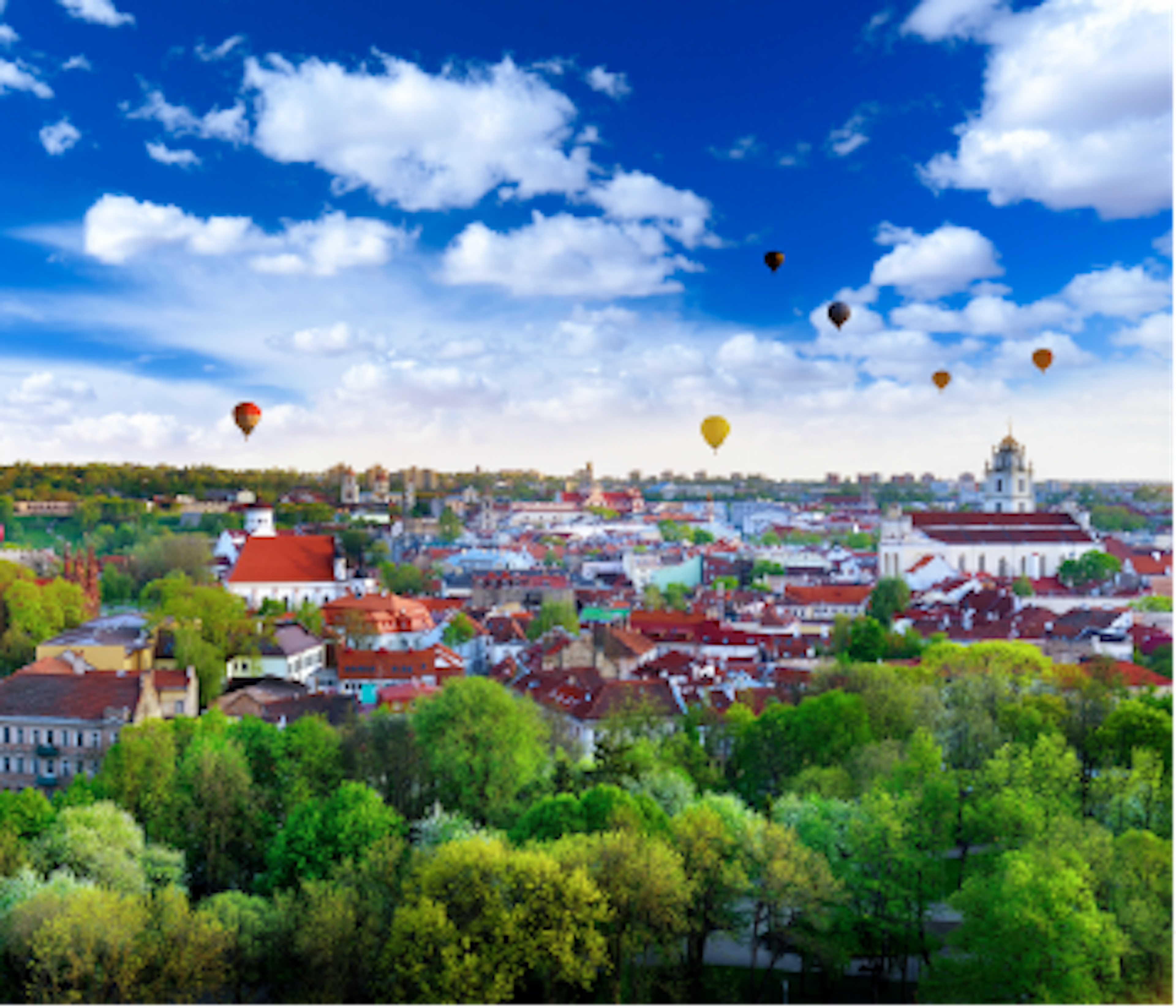 hot air balloons flying above the green city of Vilnius in Lithuania