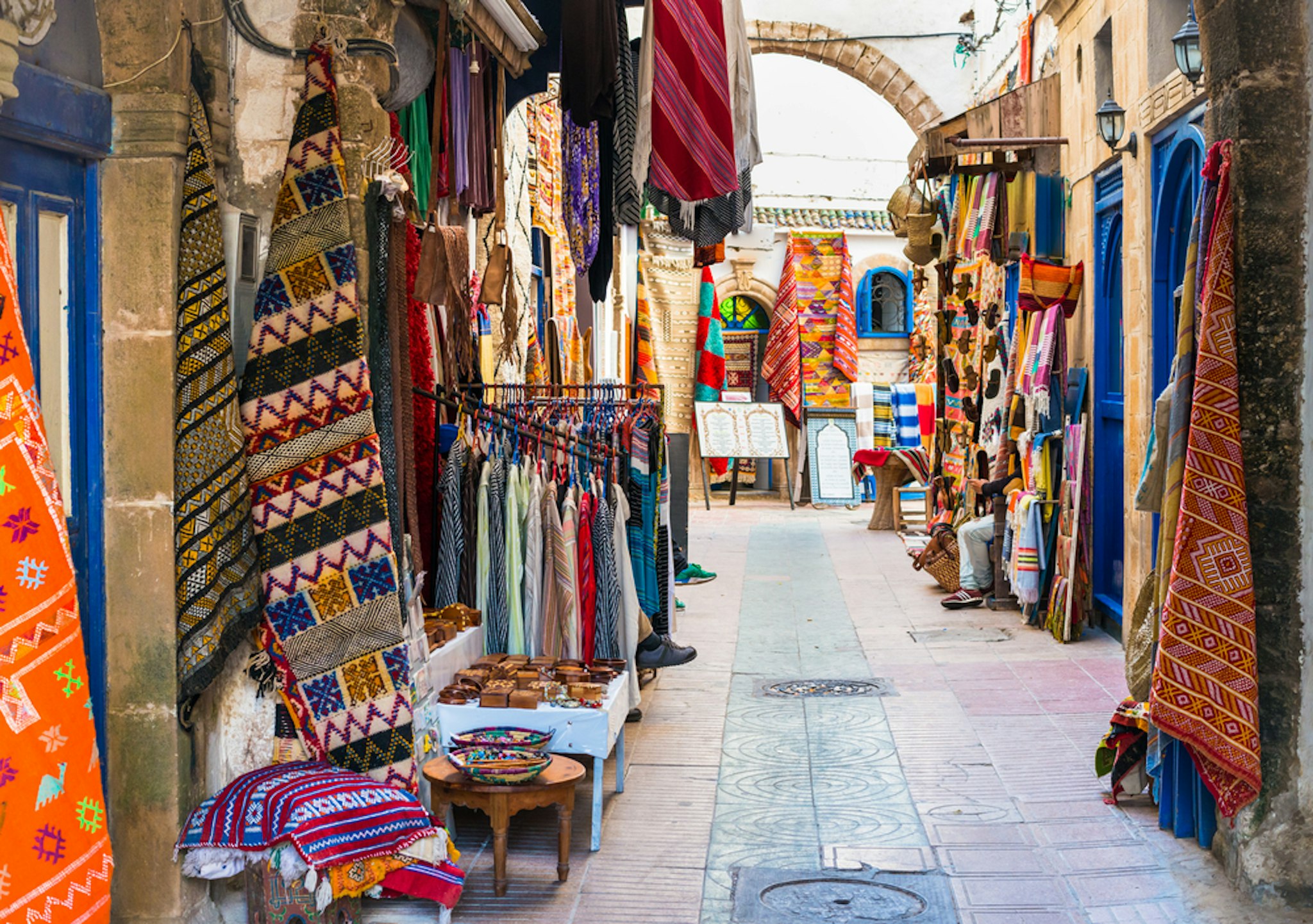 Moroccan handmade crafts, carpets and bags hanging in the narrow street of Essaouira in Morocco