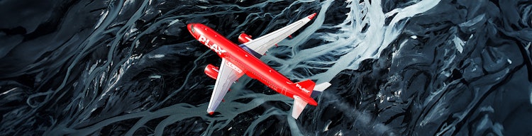 Red PLAY aircraft flying over the black sands of Iceland