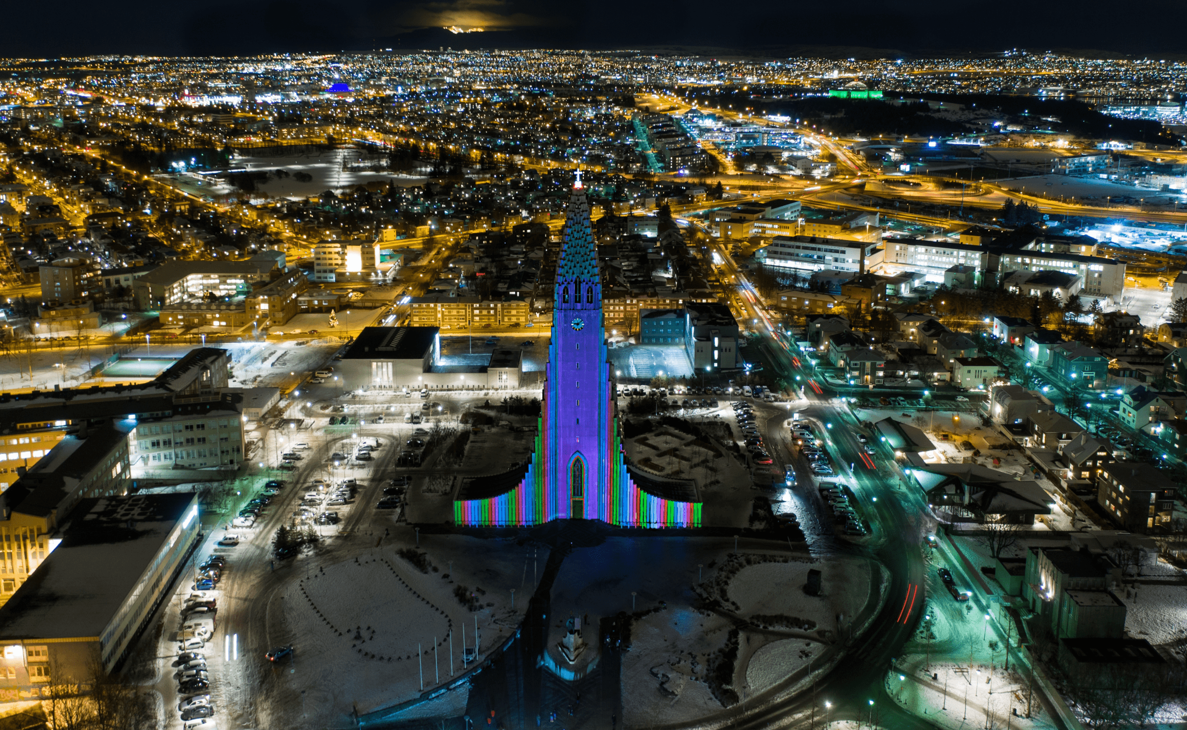 A beautifully lit Hallgrímskirkja church in Reykjavik at night with the city lights in the background