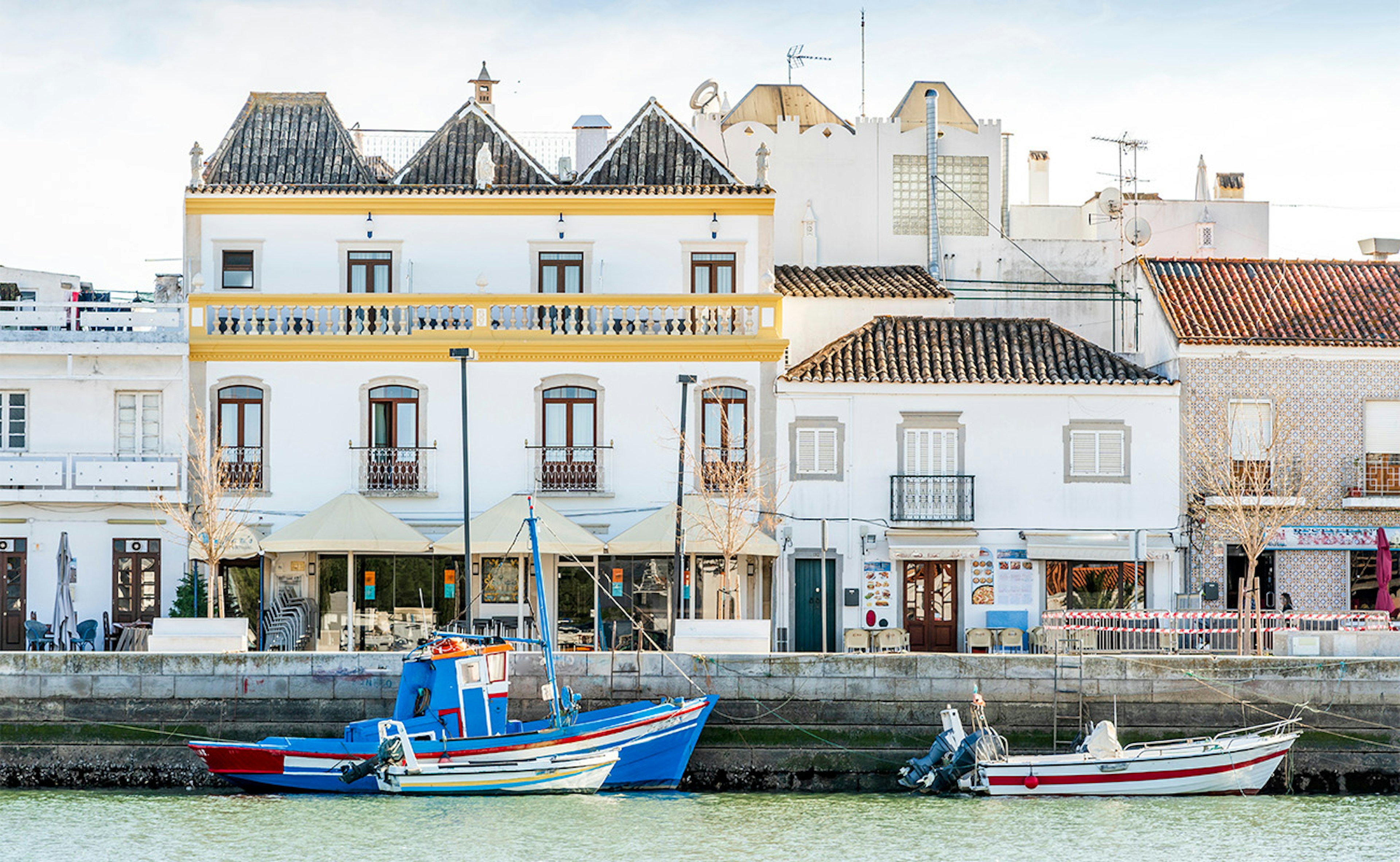 Götumynd af Tavira og bátar í ánni Gilao í Portúgal