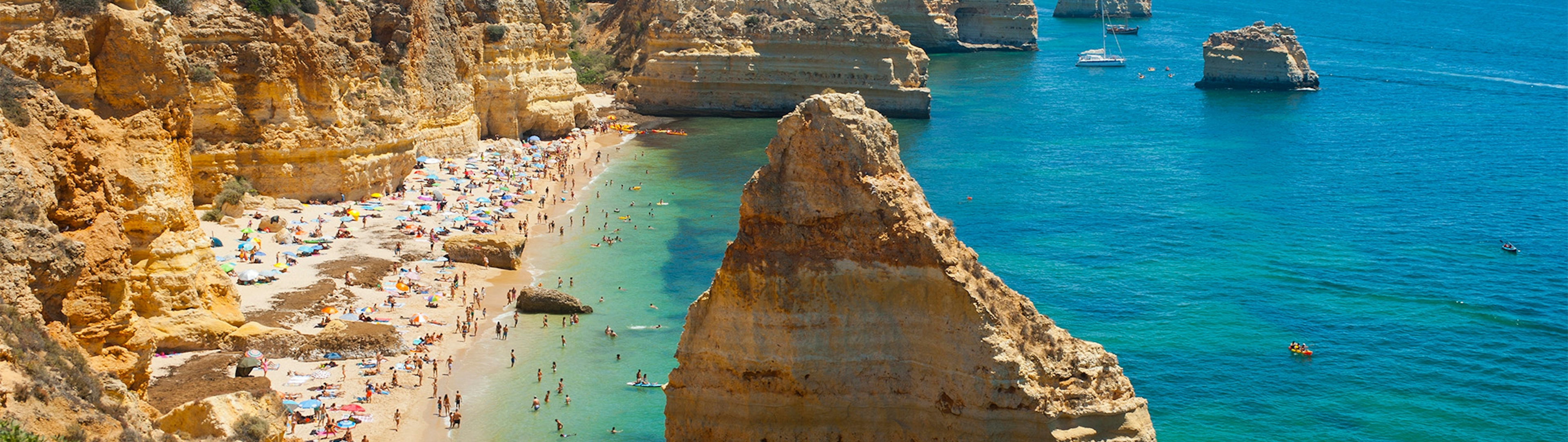 Beautiful golden beach with rocky facades and clear seas in Faro in Portugal