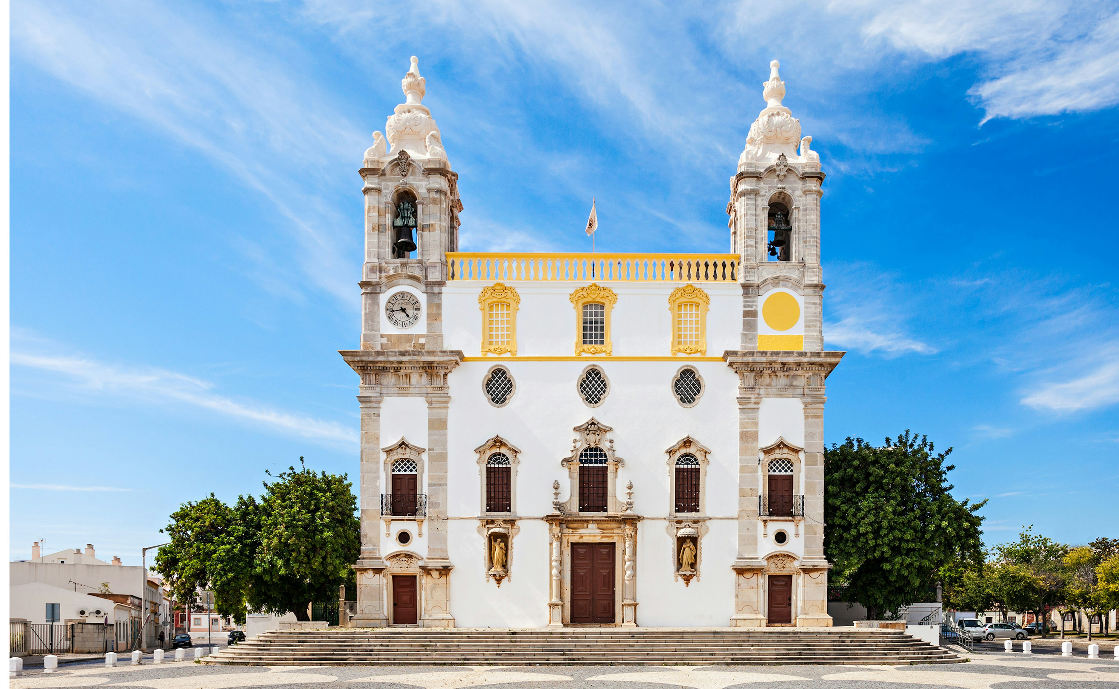 A white church in Faro with two towers and blue sky in the background.