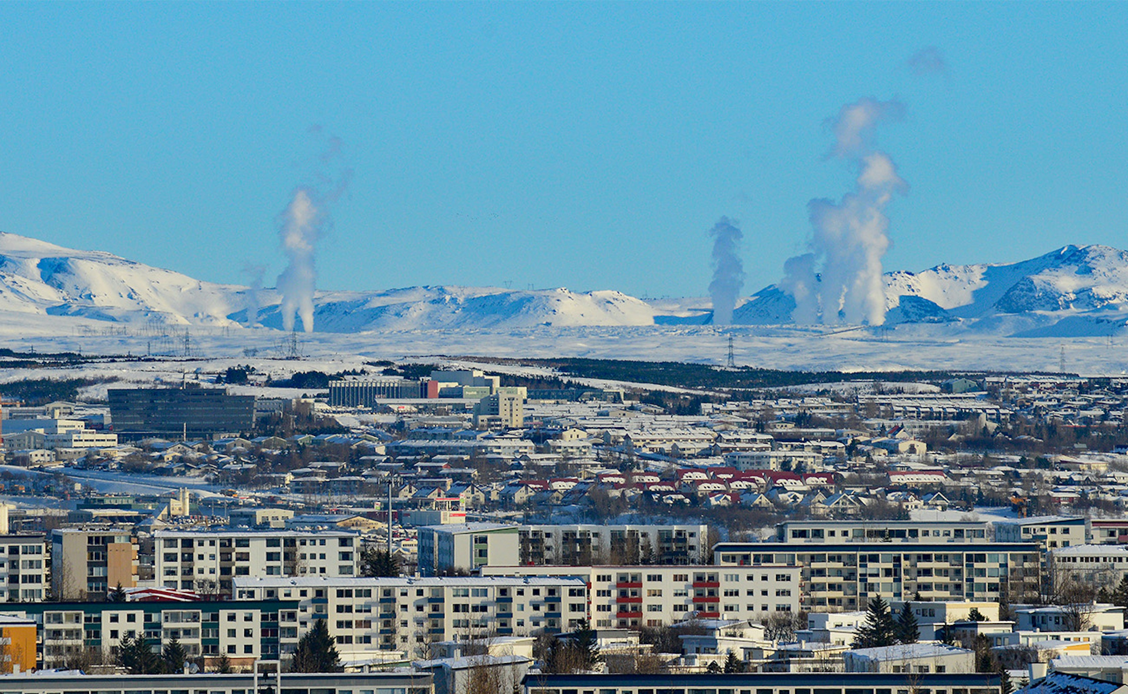 A wintery scene of Reykjavik with the geothermal steam rising from the snowy background