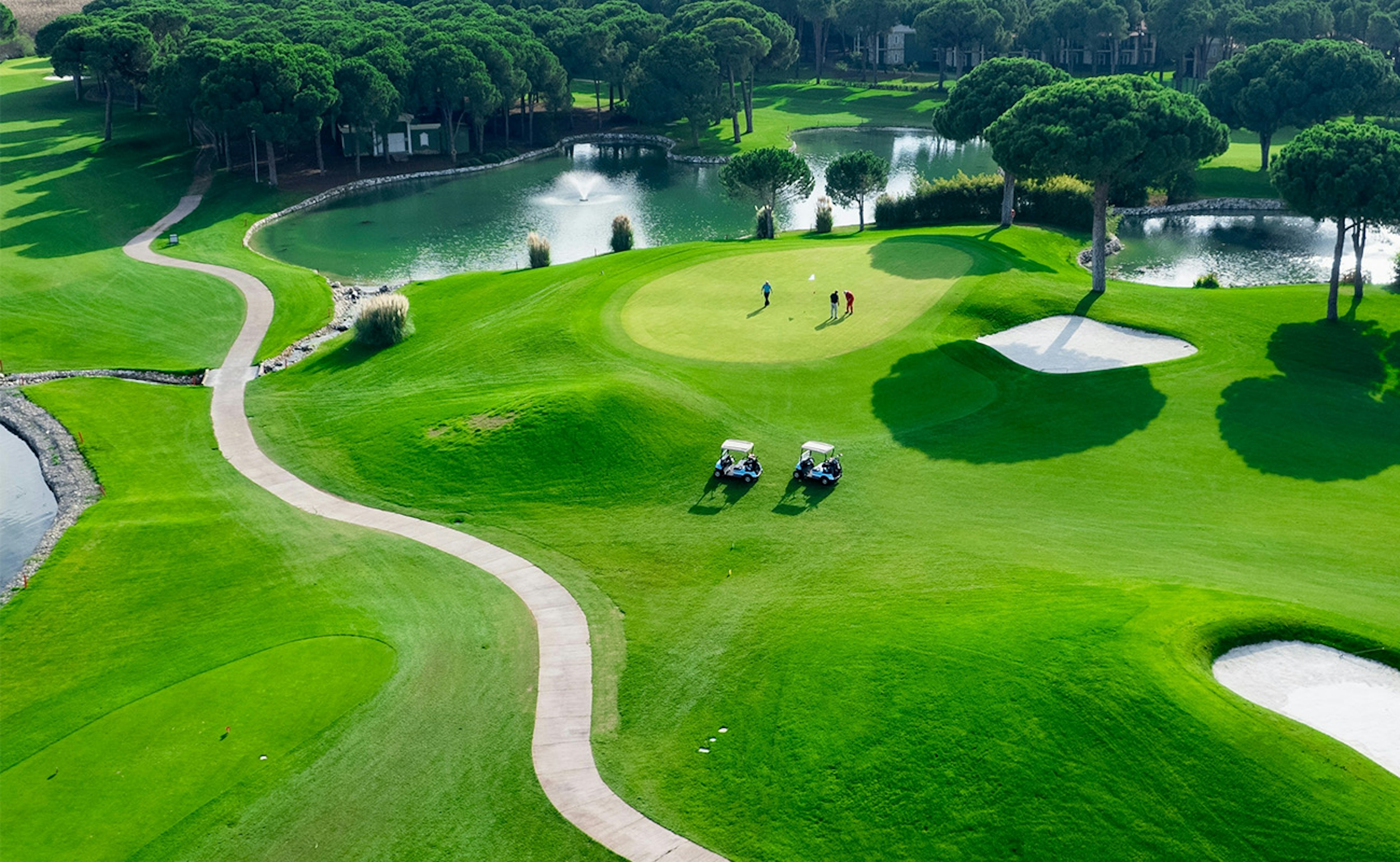 Aerial view of golfers playing on a green golf course on a sunny summer day in Antalya, Turkey.