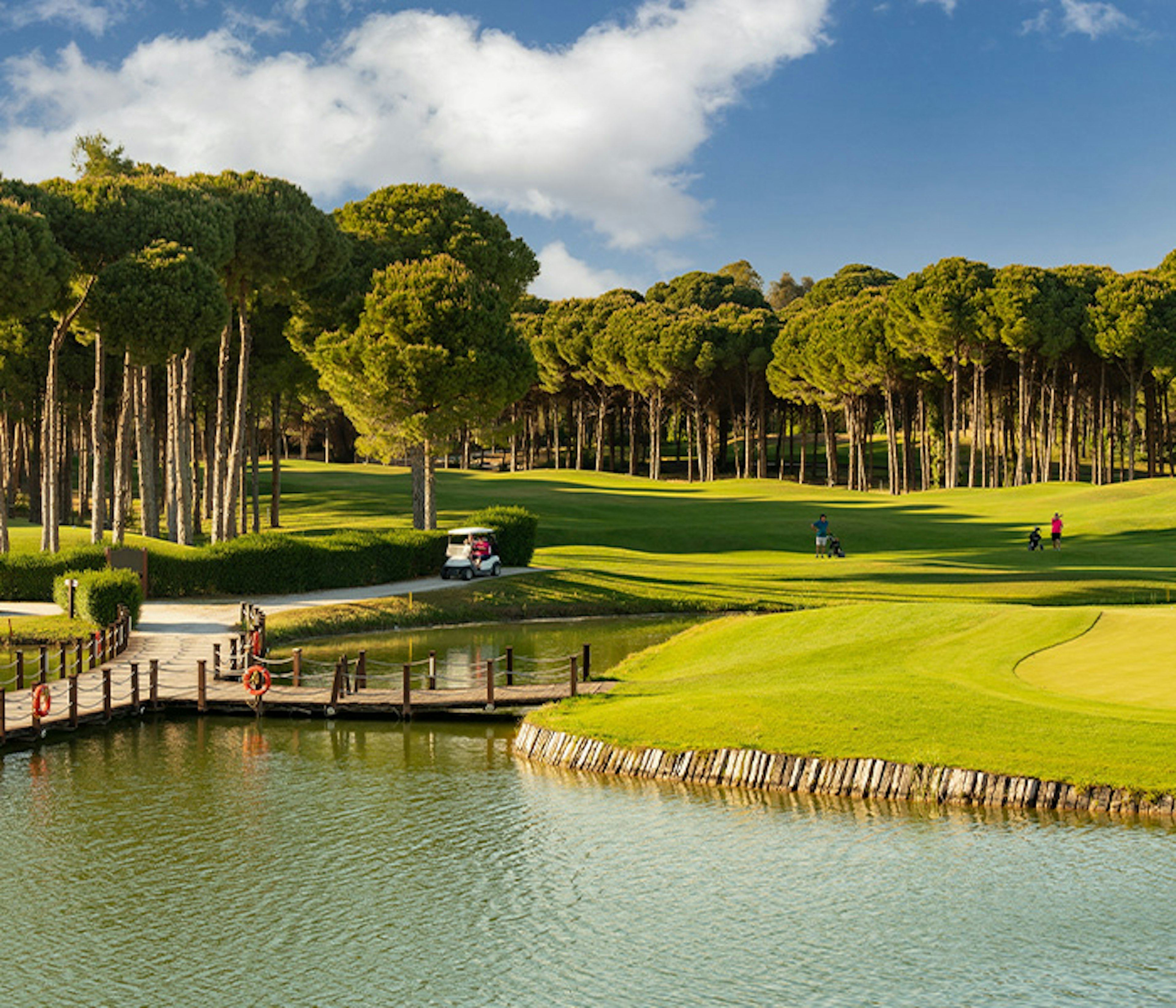 An aerial view of a green golf course with trees and a lake in Antalya, Turkey