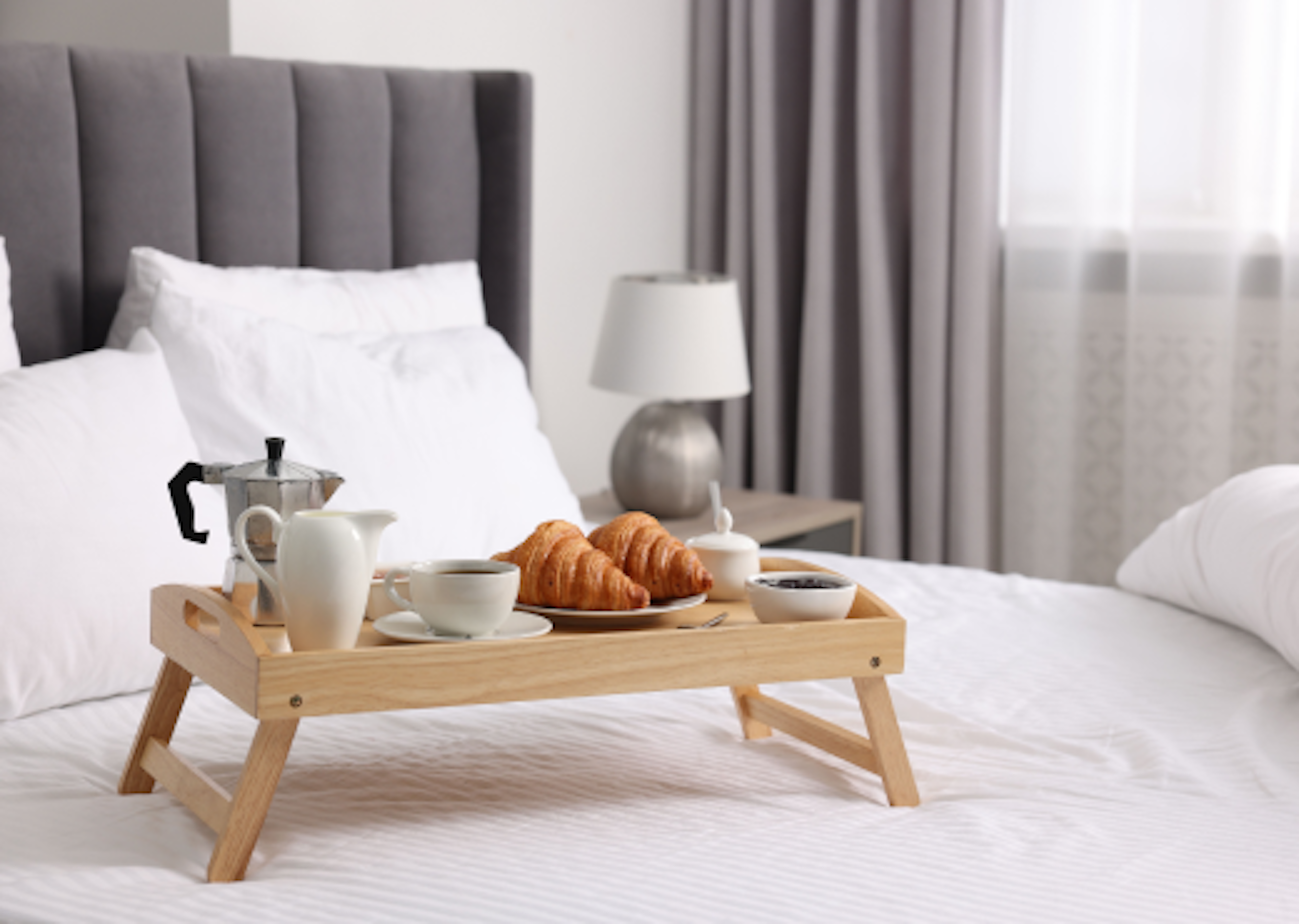 Breakfast on a bed in a hotel room.