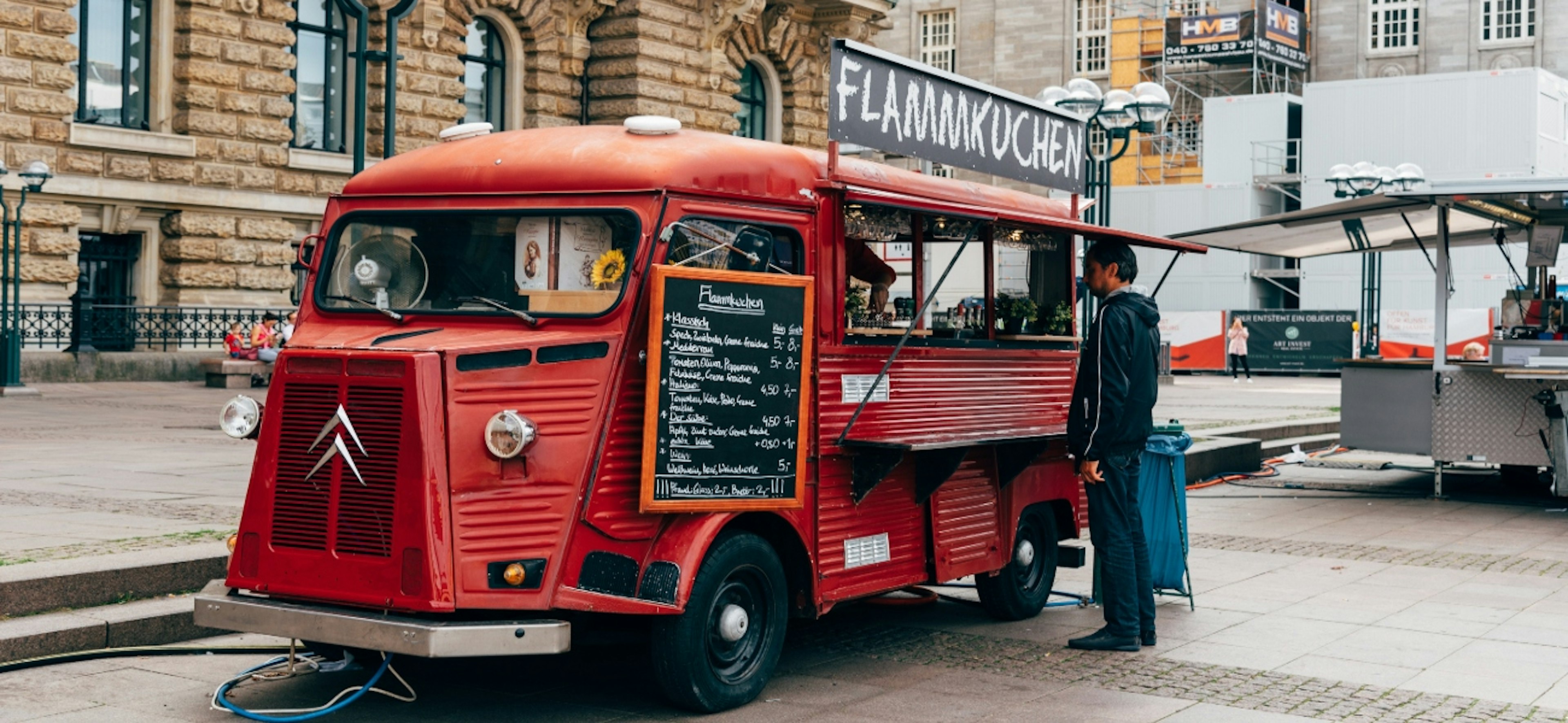 A man is buying flammkuchen or tarte flambee in a food truck