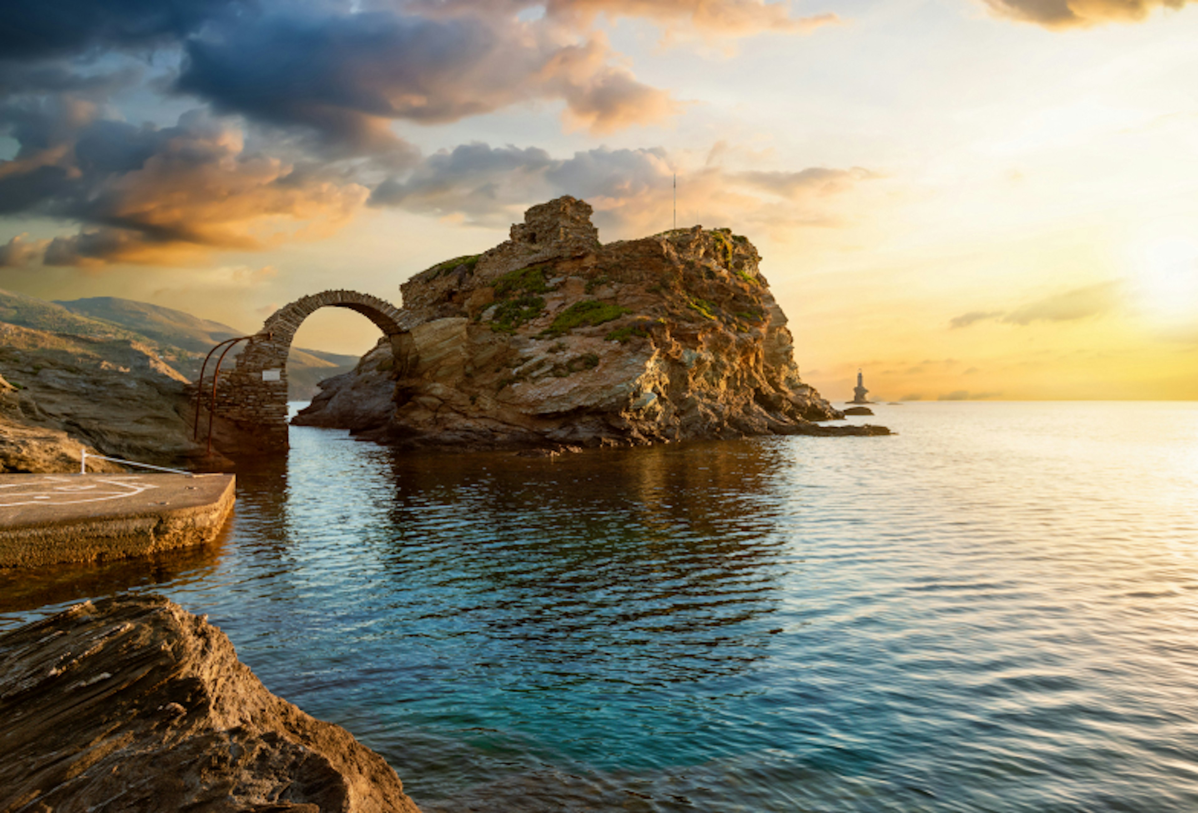 The old arched stone bridge leading to the ancient Castle of Andros island at the Cyclades of Greece during a beautiful summer sunrise