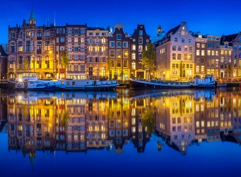 Cityscape of Amsterdam at night with reflection of buildings on water, Holland Netherlands